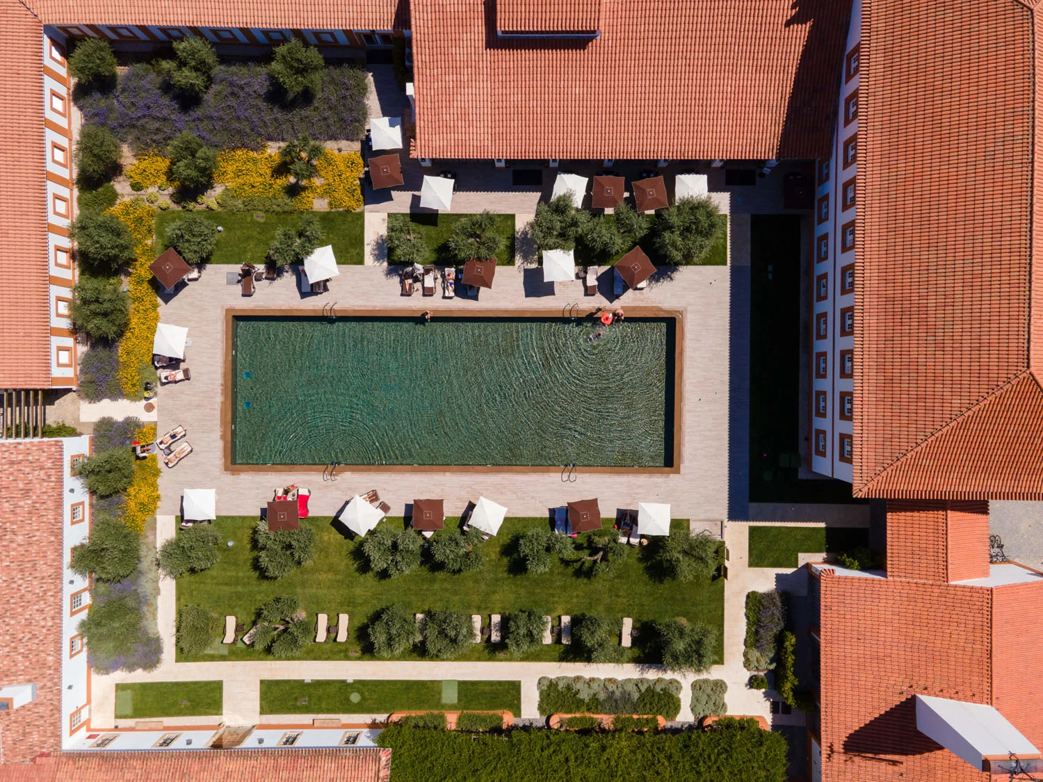 An Alentejo hotel seen from the air, its courtyard pool among terracotta roofs